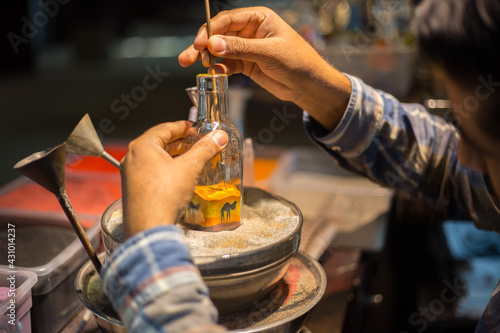 Making camel by sand in the souvenir sand bottle at the Madinat Jumeirah Souk, Dubai, UAE. Craftsman makes souvenirs in a bottle using colored sand