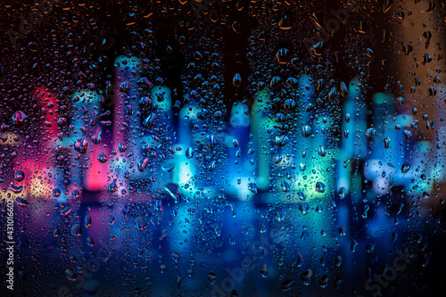 Raindrop on the window, backgorund is bluried a light of city. City life in night in rainy season abstract background. © Inception