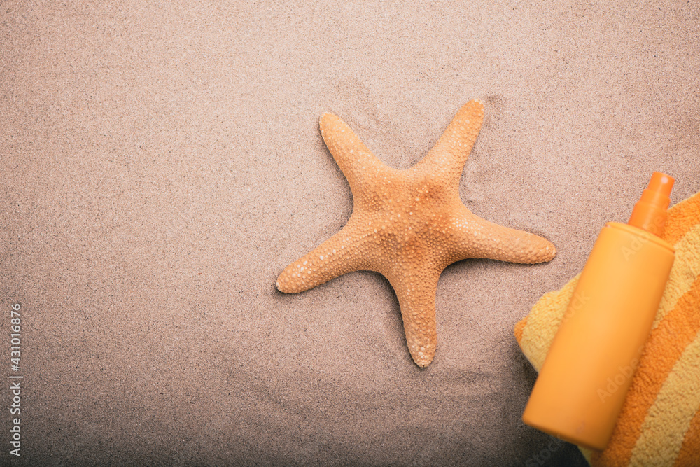 Orange tube of sun protection lotion in the sand on a beach Orange tube of sun protection lotion in the sand on a beach