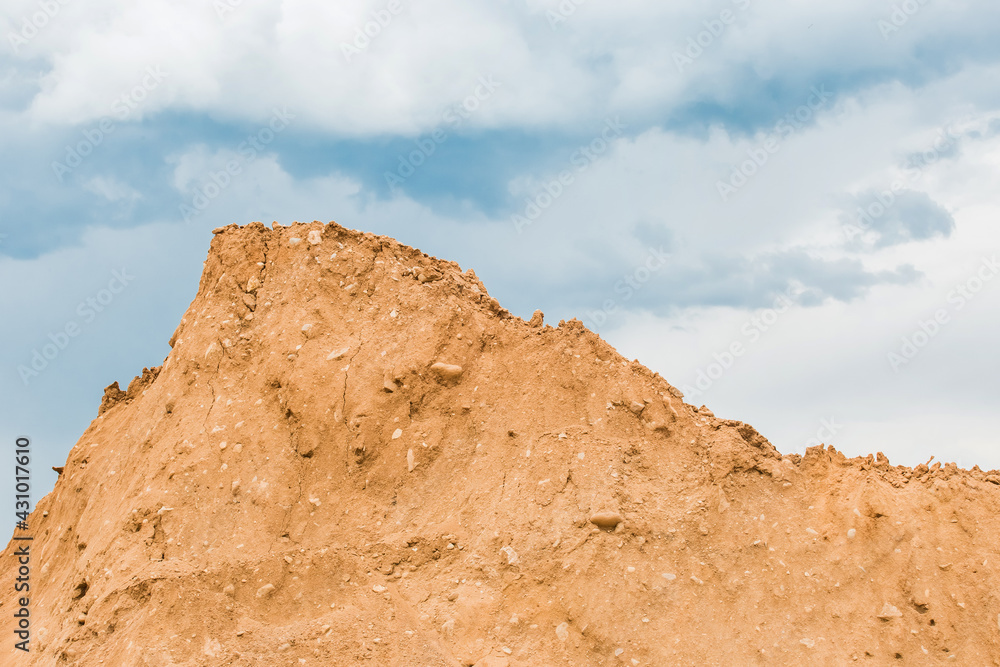 Large pile of sand nature material at a construction site against a blue sky