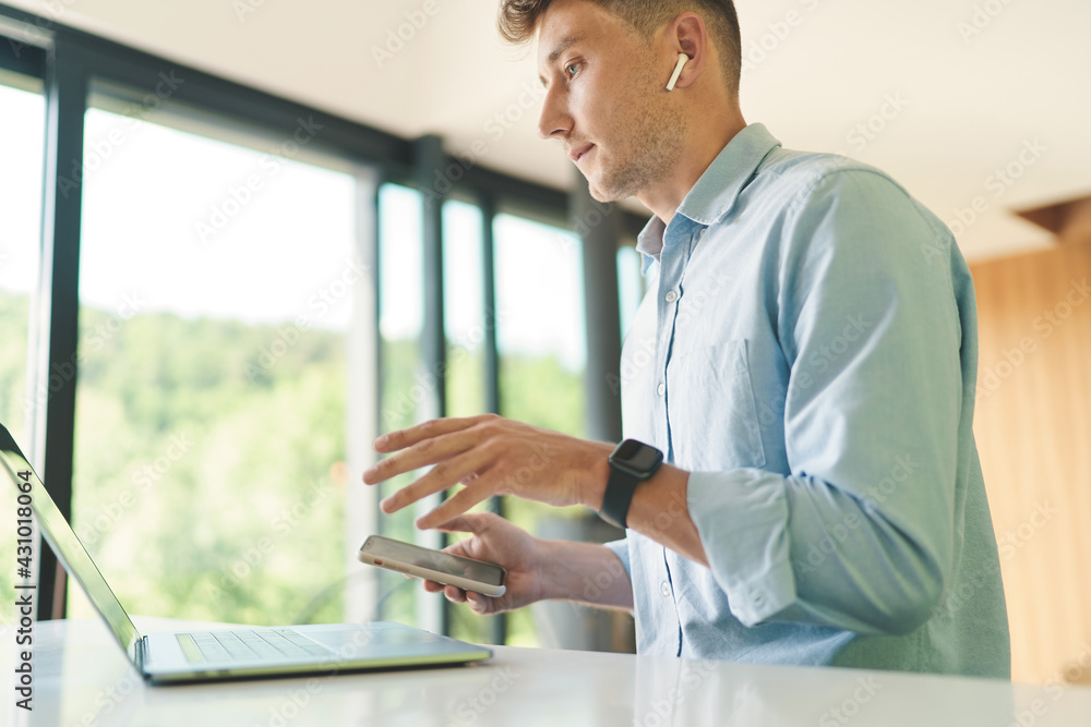 Fototapeta premium Cropped portrait of businessman working from home with laptop and smartphone