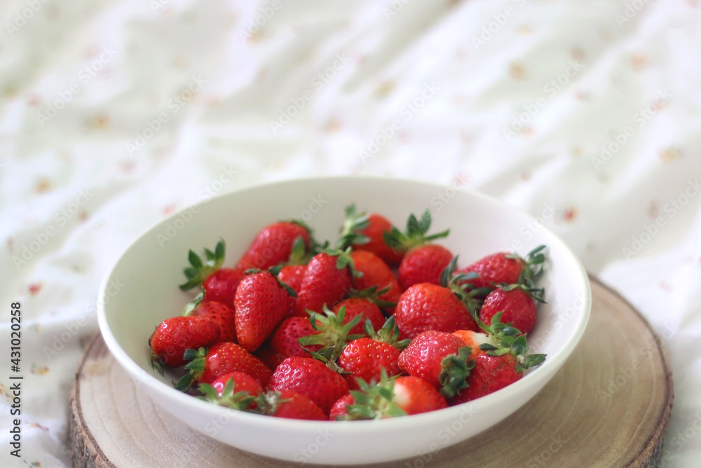 Bowl of fresh strawberries and wooden tray on a bed. Selective focus. Bowl of fresh strawberries and wooden tray on a bed. Selective focus.