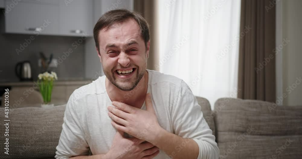 Male laughing at joke on sofa Male laughing at joke on sofa