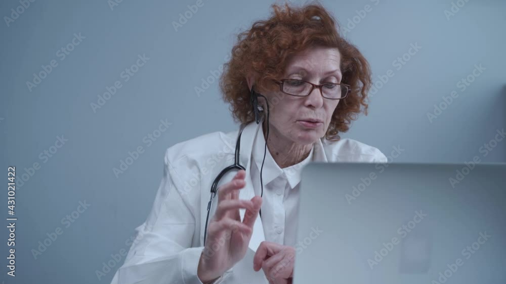 Middle aged woman general practitioner have video call with colleagues in office. Doctor talking with patient during virtual medical appointment. Physician talk by online webcam video call on laptop Middle aged woman general practitioner have video call with colleagues in office. Doctor talking with patient during virtual medical appointment. Physician talk by online webcam video call on laptop