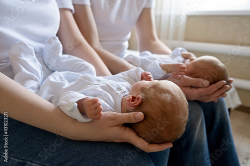 Newborn Identical twins on the bed, on a parents hands. Life style, emotions of kids. Infant Babies With Copy Space