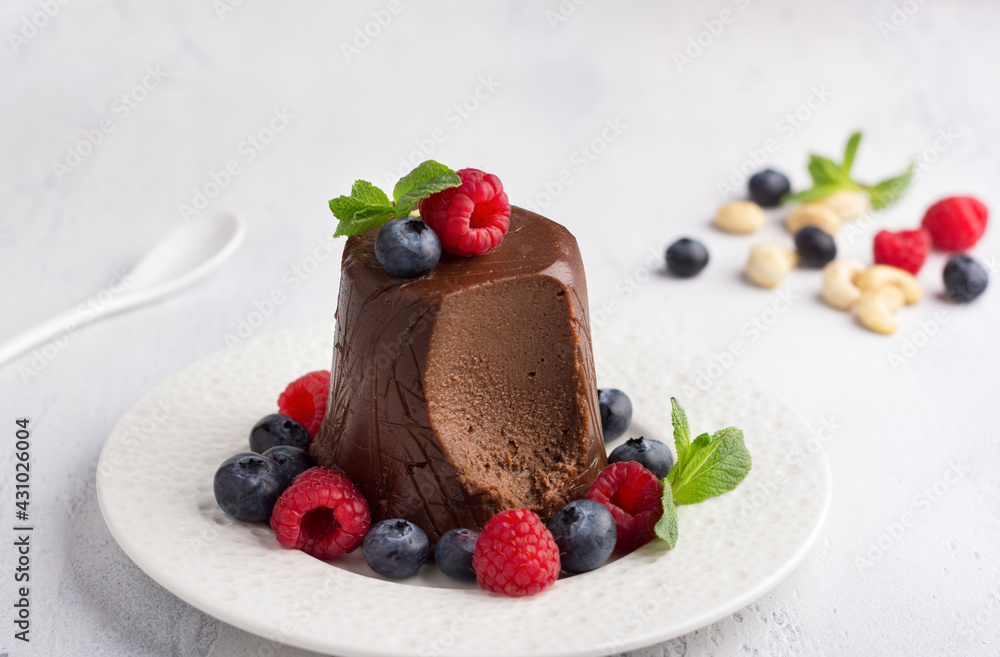 Vegan cashew and chocolate Easter paskha, delicious dessert with berries and mint on light blue background Vegan cashew and chocolate Easter paskha, delicious dessert with berries and mint on light blue background