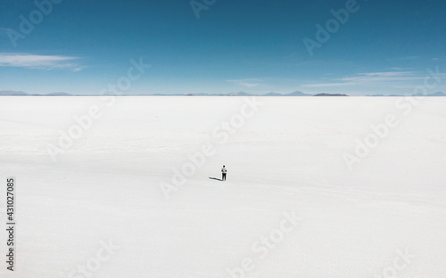 Isolated tourist enjoying endless infinite vastness dreamy landscape of white salt flat lake Salar de Uyuni in Bolivia