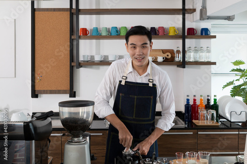 Young Barista hand holding ground coffee for preparing coffee. Barista preparing portafilter before making caffee in a cafe shop. Barista holding portafilter tamping and preparing cup of coffee.