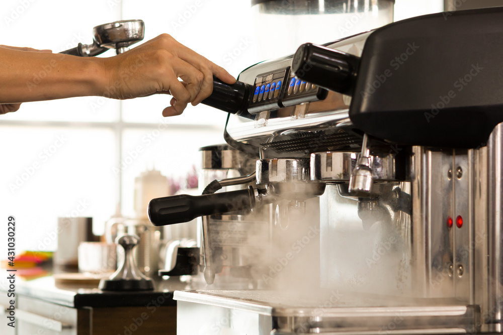 Young Barista preparing and making espresso with coffee machine. Barista preparing portafilter before making cappuccino in a coffee shop. Young Barista preparing and making espresso with coffee machine. Barista preparing portafilter before making cappuccino in a coffee shop.