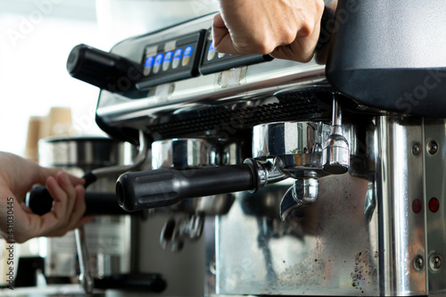 Young Barista preparing and making espresso with coffee machine. Barista preparing portafilter before making cappuccino in a coffee shop. 