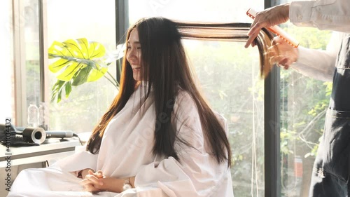 Male hairdresser trimming hair to beautiful young woman in beauty hair salon.