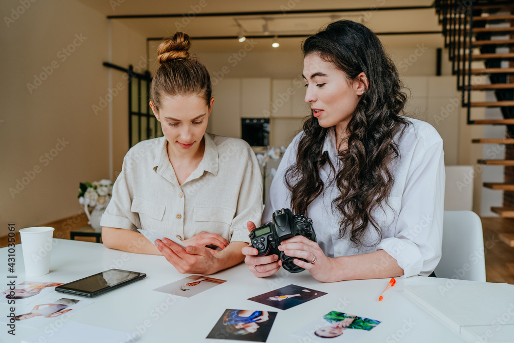 Two young women selecting photos on the camera indoor