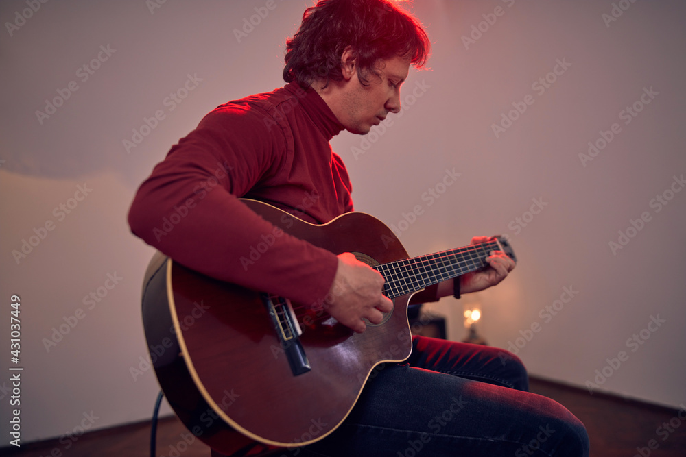 Obraz premium Male musician playing acoustic guitar on the amplifier in retro vintage room.