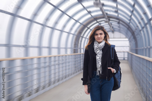 young woman walks quickly through the covered walkway © Evgeny