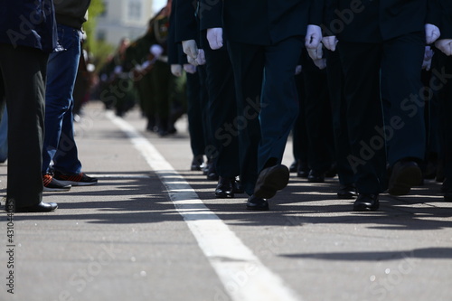a solemn parade in the city square during a military holiday, the best soldiers marching synchronously in a column of systems, stamping step with weapons in hand, demonstration of military power