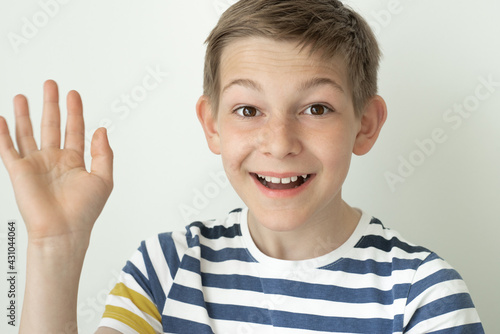 Portrait of happy handsome teen boy on white wall background with emotional gesture