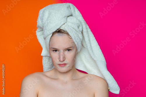 A girl with wet hair and with a cosmetic mask looks depressively into the lens
