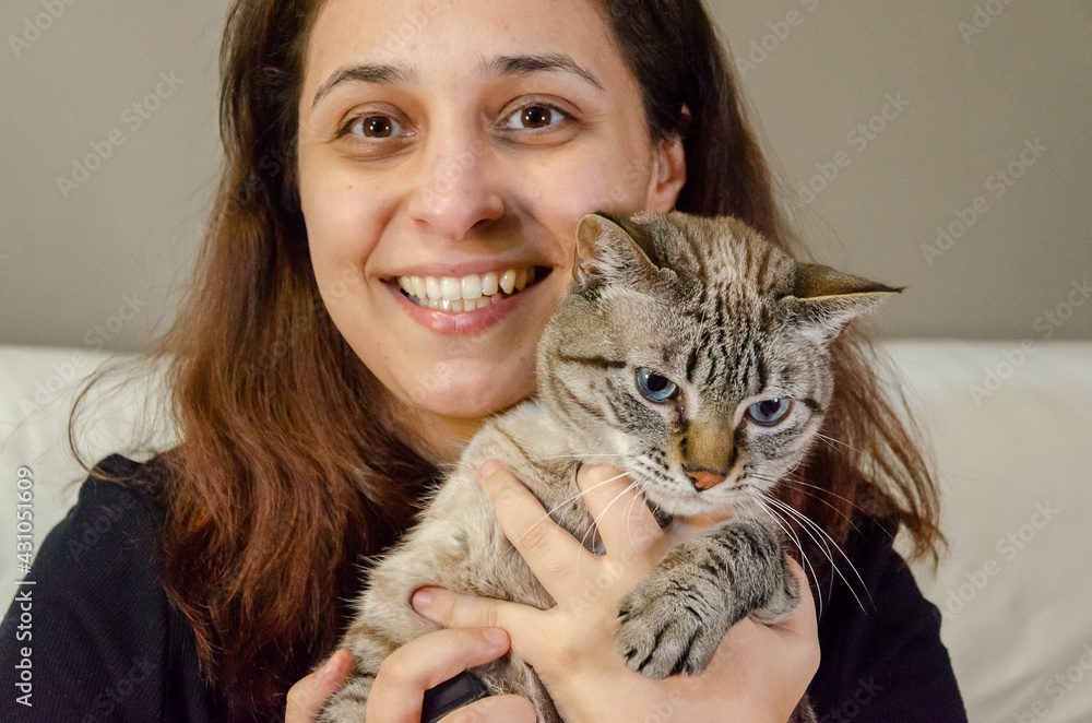 woman holding a tabby cat looking at camera woman holding a tabby cat looking at camera