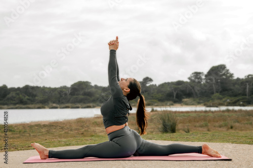 Dark haired, white Caucasian woman doing stretching and breathing before practicing yoga or pilates, Hanumanasana (Monkey God pose)
