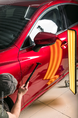 The technician removes dents on the car using the method without painting. PDR. Car body repair.