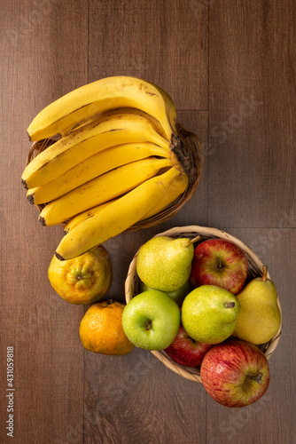tropical fruit basket in detail on wooden surface, black background, selective focus.