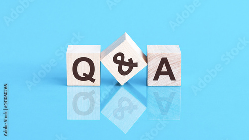 q and a word is made of wooden building blocks lying on the blue table, concept photo