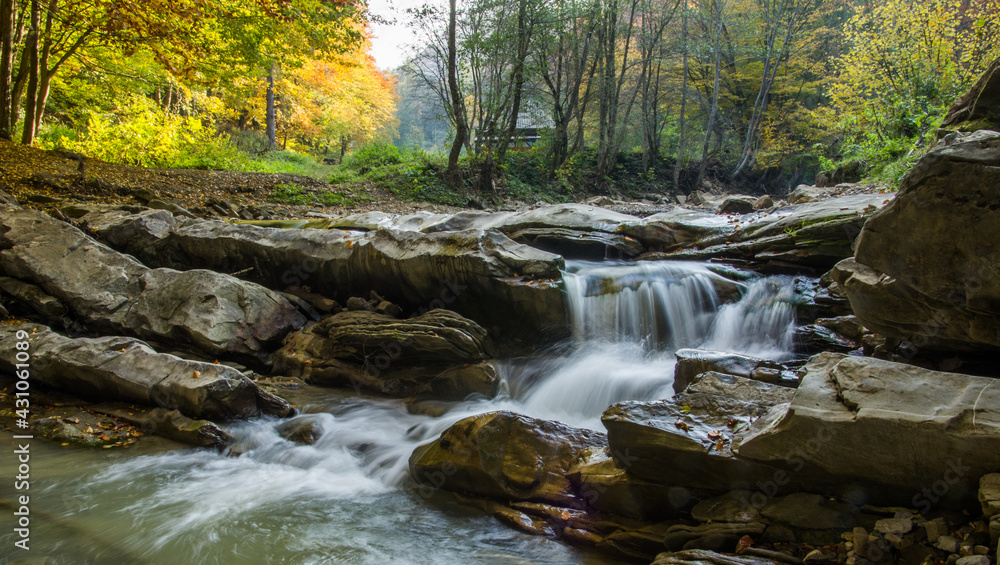 The fast flow of a mountain river among the stones. Long exposure. Motion blur. Selective focus.