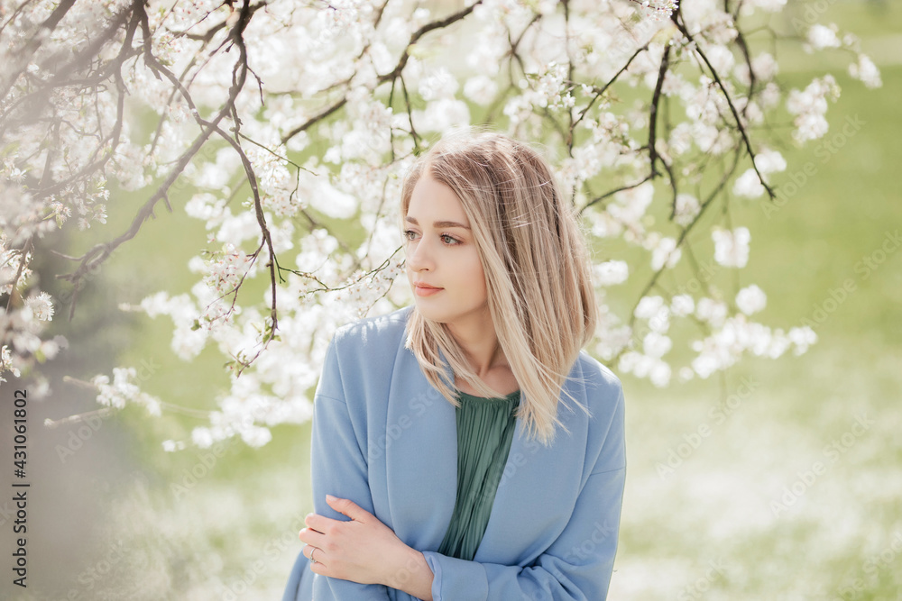 Portrait of young blonde woman standing near the apple tree. Spring time Portrait of young blonde woman standing near the apple tree. Spring time