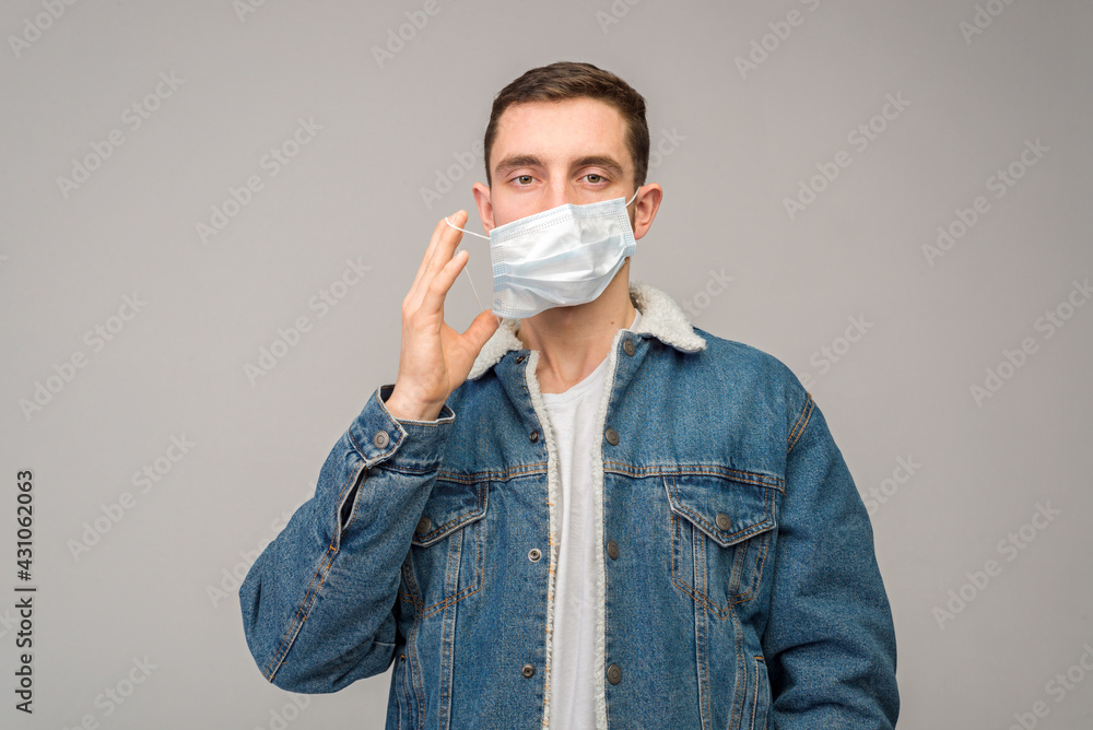 Portrait of a young man, on a light background, with a protective mask on his face. Prevention of coronavirus, flu. Portrait of a young man, on a light background, with a protective mask on his face. Prevention of coronavirus, flu.