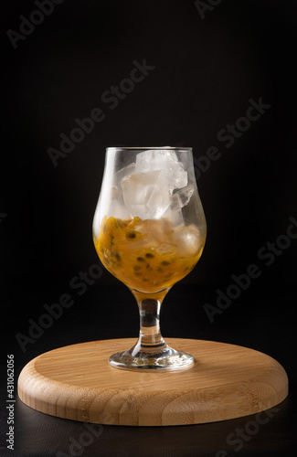 Brazilian Drink, Sake caipirinha with passion fruit in a bowl, on dark round wooden surface, black background, selective focus. © Milton Buzon
