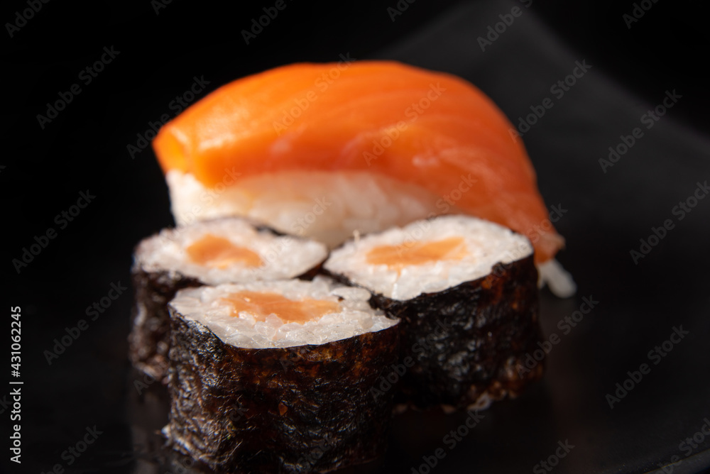 Sushi, beautiful arrangement of sushi made on black plate on dark surface, black background, selective focus. Sushi, beautiful arrangement of sushi made on black plate on dark surface, black background, selective focus.