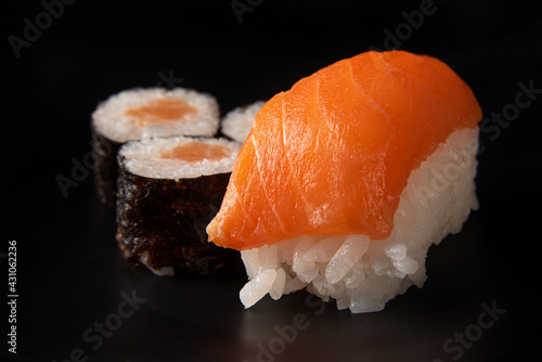 Sushi, beautiful arrangement of sushi made on black plate on dark surface, black background, selective focus.