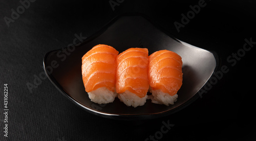 Sushi, beautiful arrangement of sushi made on black plate on dark surface, black background, selective focus.
