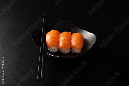 Sushi, beautiful sushi arrangement with hashi made on black plate on dark surface, black background, selective focus.