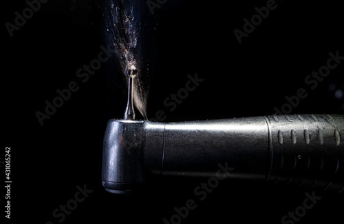 A dental drill or handpiece with burr sprays water photo