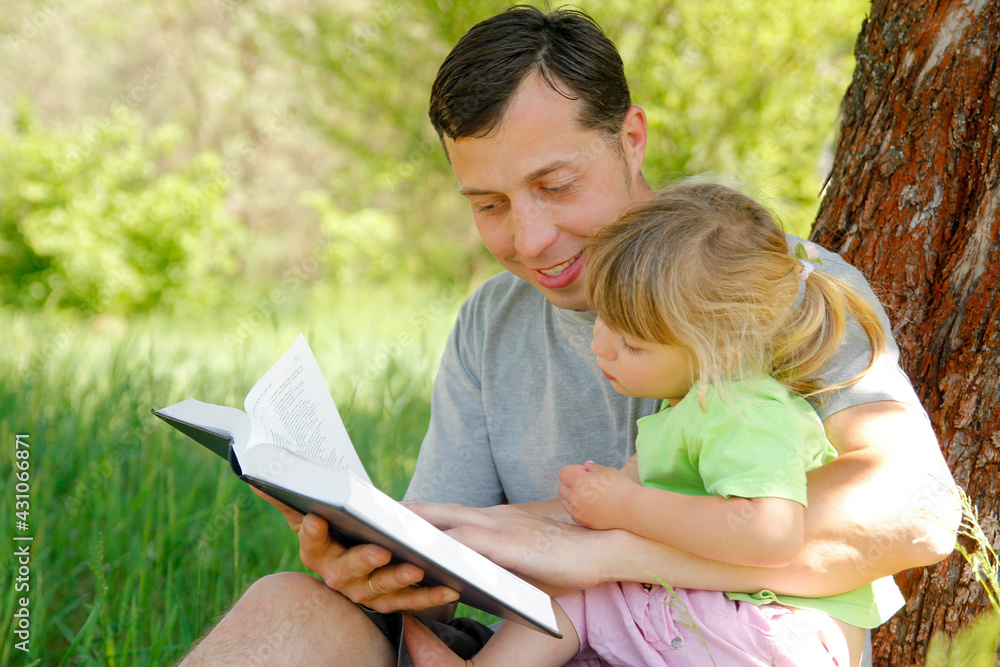 happy father with a child reading a book on the nature of the Bible happy father with a child reading a book on the nature of the Bible