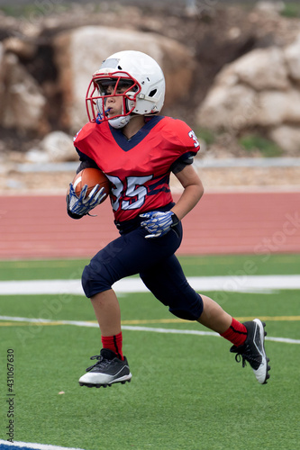 Young athletic boy playing in a youth tackle football game