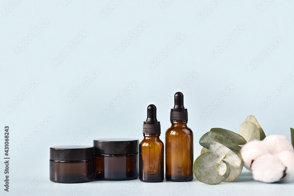 Brown glass bottle and eucalyptus with cotton on a light blue background. Eco-friendly organic natural cosmetics for skin and body care. Copy Space Brown glass bottle and eucalyptus with cotton on a light blue background. Eco-friendly organic natural cosmetics for skin and body care. Copy Space