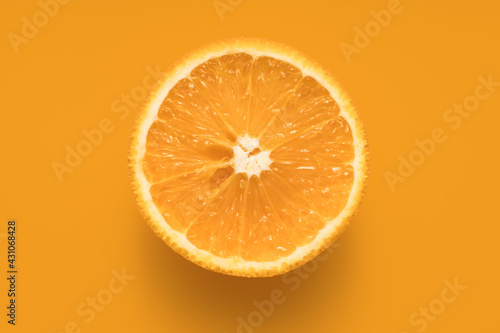 Half orange on orange background, flat lay