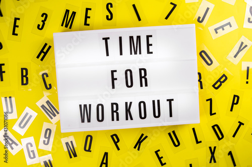 Lightbox with text TIME FOR WORKOUT on yellow background with black letters randomly scattered. Concept of everyday training, keep-fit, physical exercise session, health care, active lifestyle