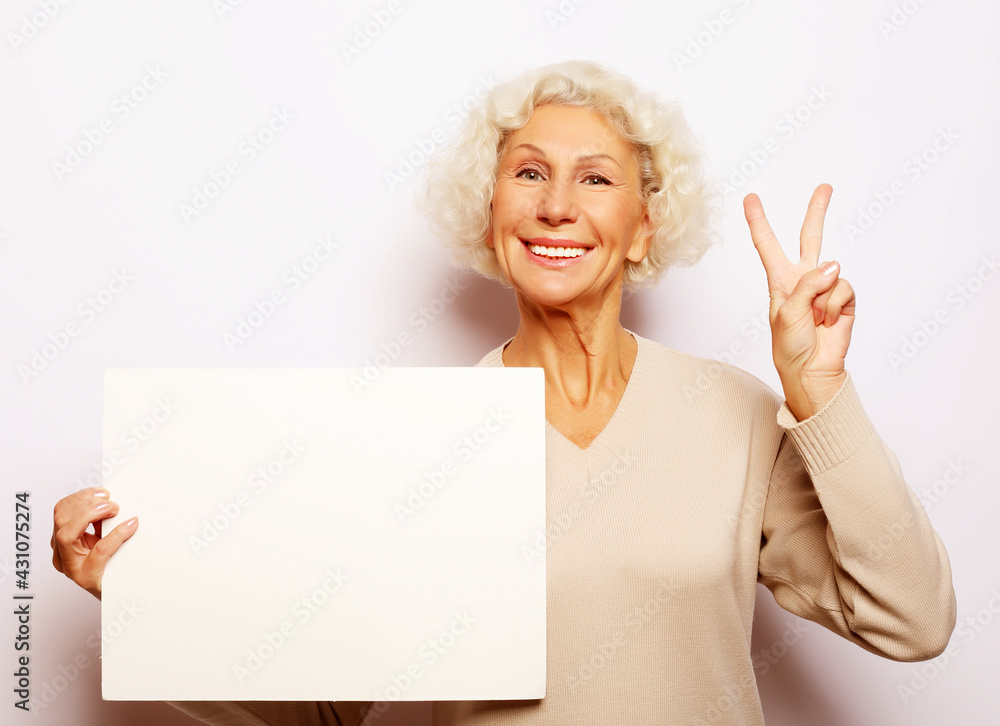 Aged woman with blank advertising board or copy space. Portrait of handsome expressive grandmother. Aged woman with blank advertising board or copy space. Portrait of handsome expressive grandmother.