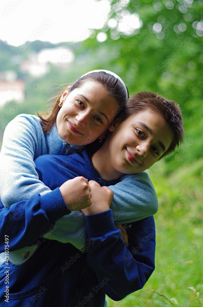 Young woman mom hugs boy son. Happy family relationships. Outdoor, park, nature, backyard