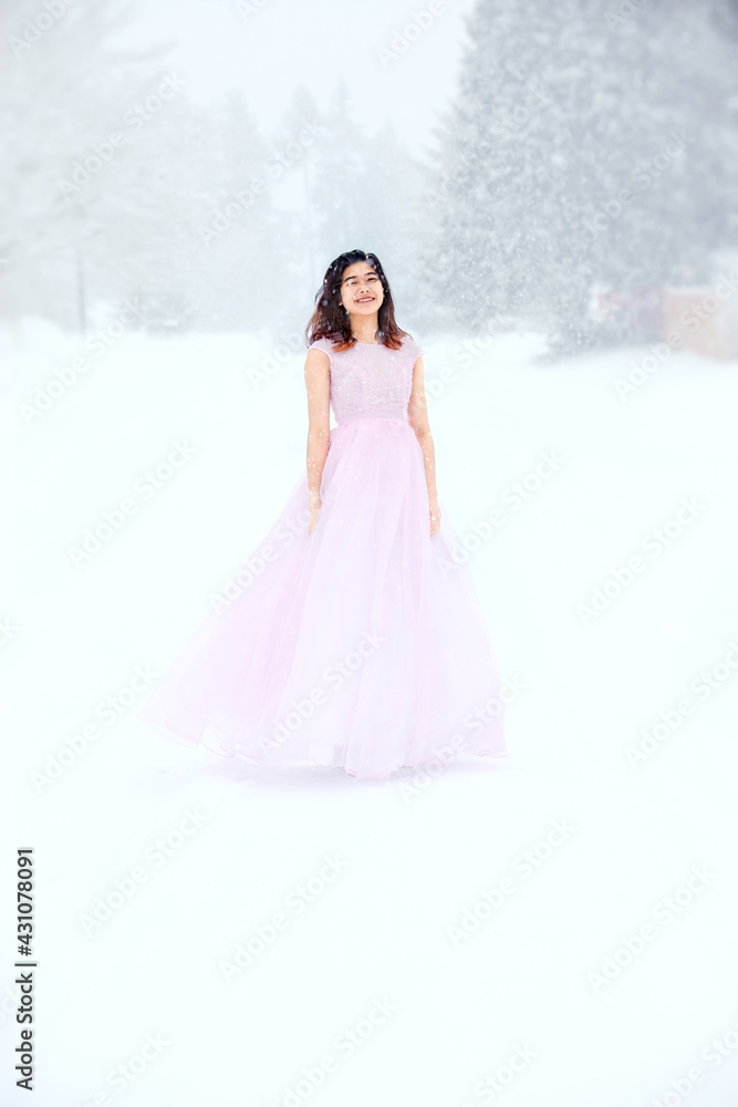 Teen girl in pink formal dress on snowy day outdoors
