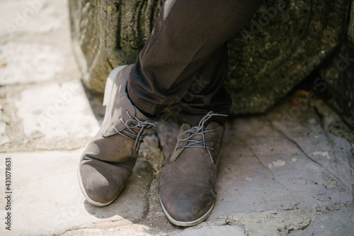 Groom stands in lace-up shoes on the cobblestone pavement © Nadtochiy