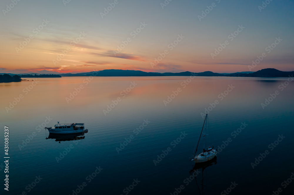 Sunrise waterscape with boats, light cloud and reflections Sunrise waterscape with boats, light cloud and reflections