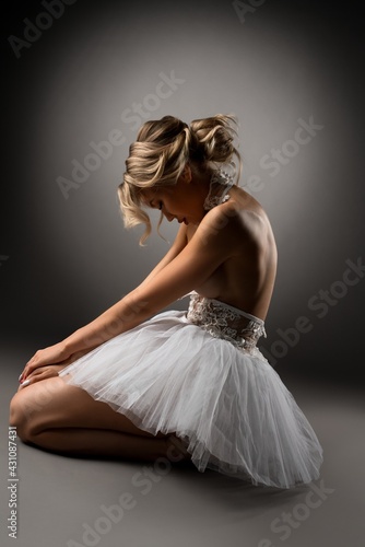 Topless ballerina kneeling on floor during dance