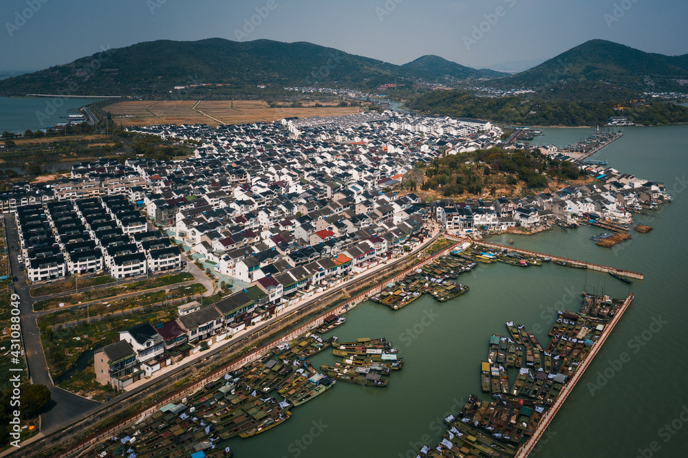Aerial of a Chinese old fishing village, with rows of traditional houses and fishing boats in the harbor