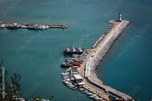 Top view of a pier  with a beautiful white lighthouse and a pier with many boats and yachts on the background of the blue sea photo