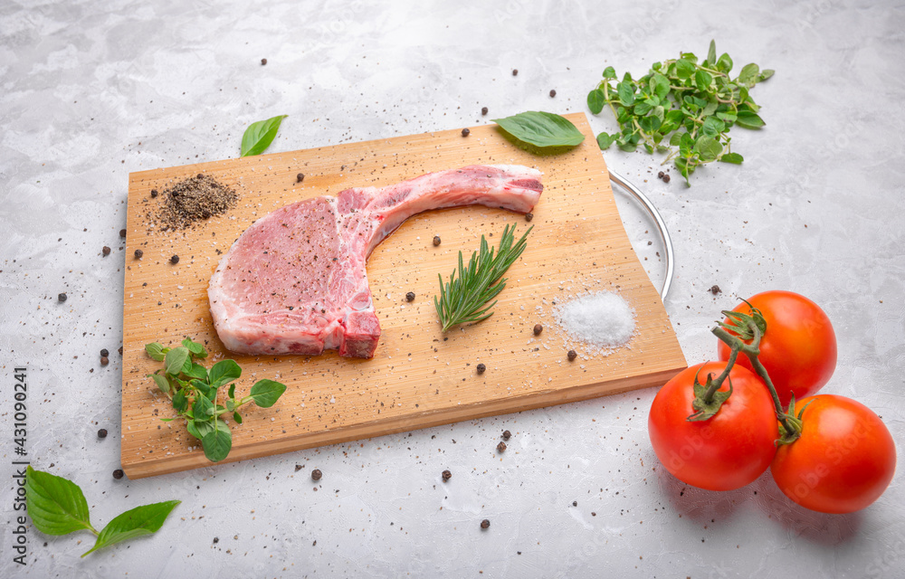 Fresh raw pork with spices and rosemary, oregano and black pepper on wooden slate, on white marble background, pork chop on a bone. Fresh raw pork with spices and rosemary, oregano and black pepper on wooden slate, on white marble background, pork chop on a bone.