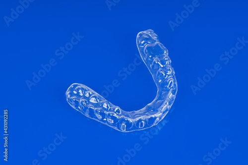 Invisible orthodontics cosmetic brackets on blue background. Tooth aligners, for beautiful smile.